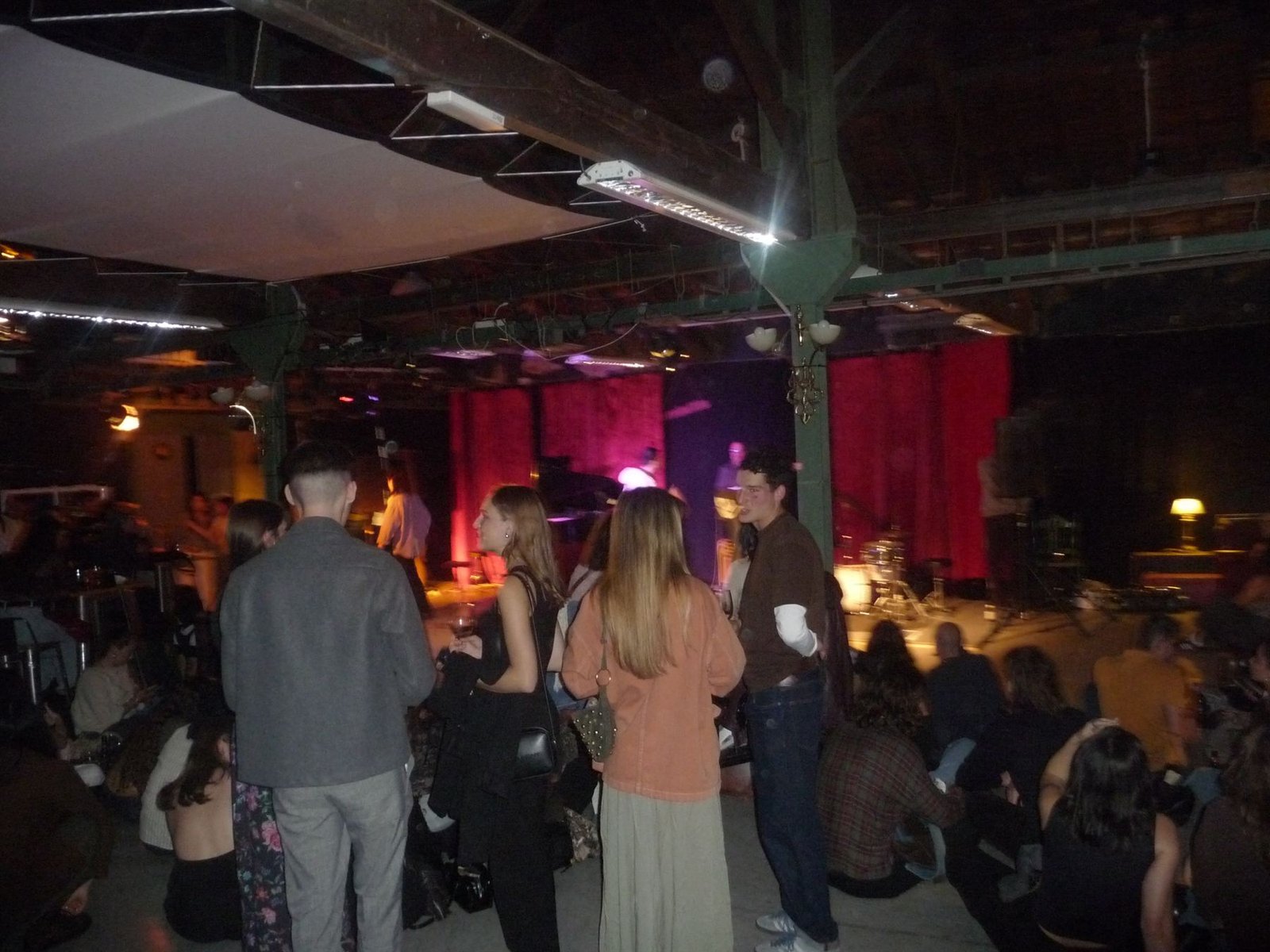 Sala llena de gente frente al escenario iluminado en rojo durante una noche de Jazzfera