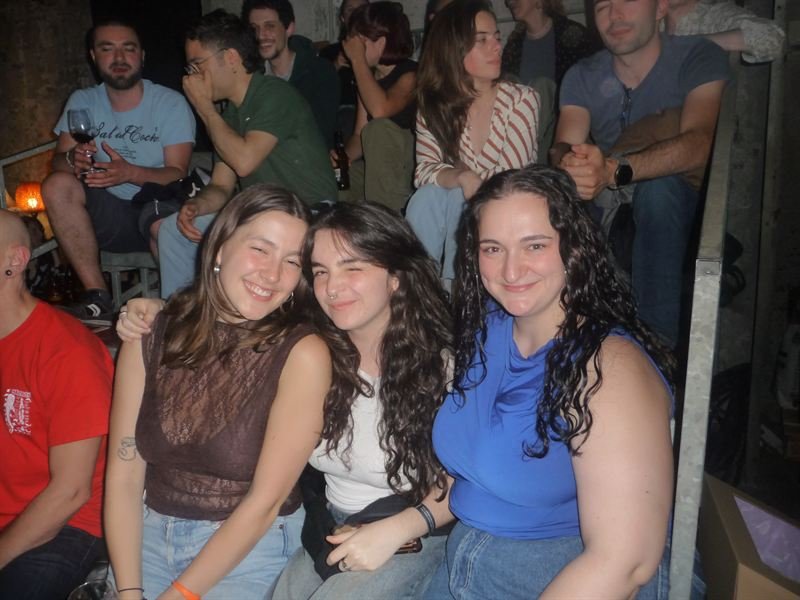 Tres amigas abrazadas entre el público